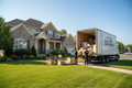 Elite Quick Movers crew in branded shirts loading a moving truck in front of a residential home for long distance move